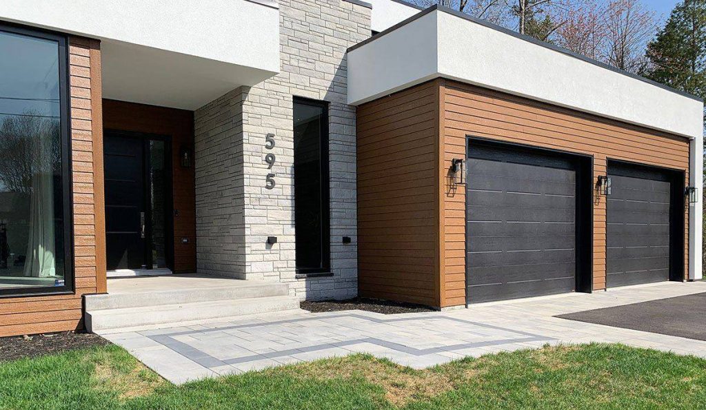 Entrée de pavé encadrée devant une maison blanche et bois