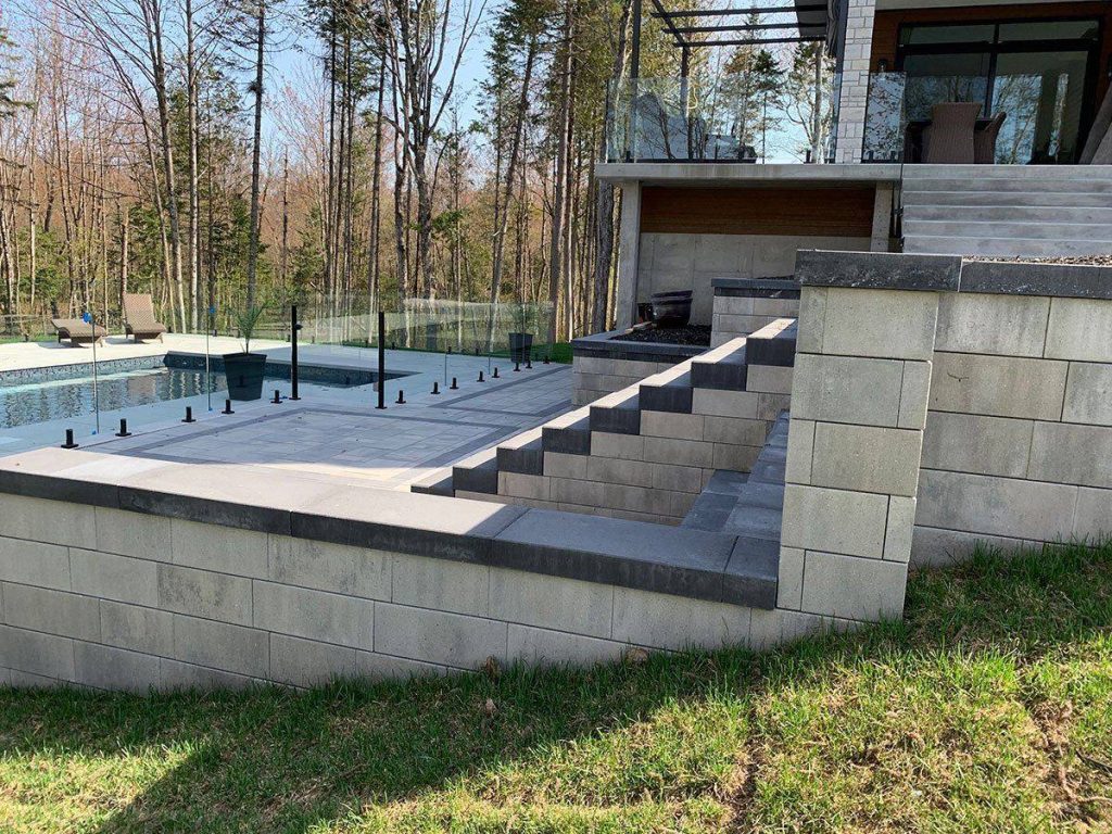 Escalier de pierre menant à la piscine, bordée d’un garde-corps de verre